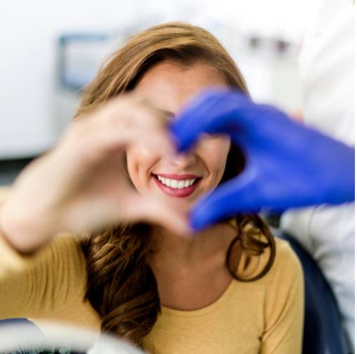 Woman smiling and making a heart shape with her dentist