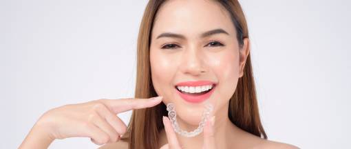 smiling woman holding invisalign braces in studio, dental healthcare and Orthodontic