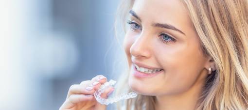  Young attractive woman holding - using invisible braces or trainer.v